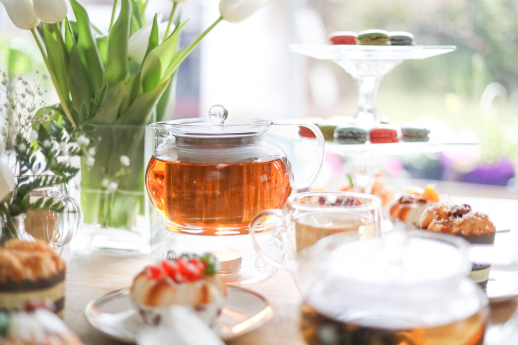 Teabloom glass teaware display with fresh white tulips and pastries as a bridal shower tea party idea.