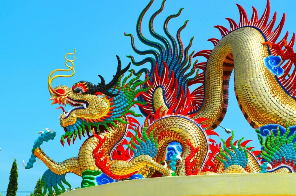 A statue of a gold-scaled Chinese dragon with colorful highlights in light and dark blue, green, and red as one of the Chinese Zodiac personalities.
