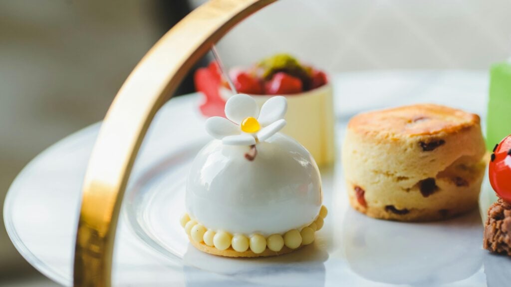 Small pastries, cakes, and a scone on the top of a three-tiered stand.