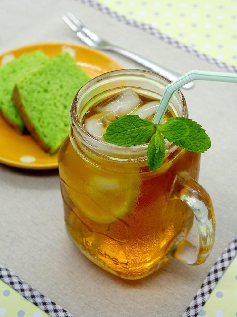A glass mug of southern sweet tea with a straw and a sprig of mint, with lemon slices as an example of one of the teas from around the world.