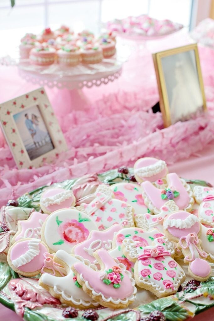 A pink tablescape for a garden tea party baby shower with pink cupcakes and decorated sugar cookies.