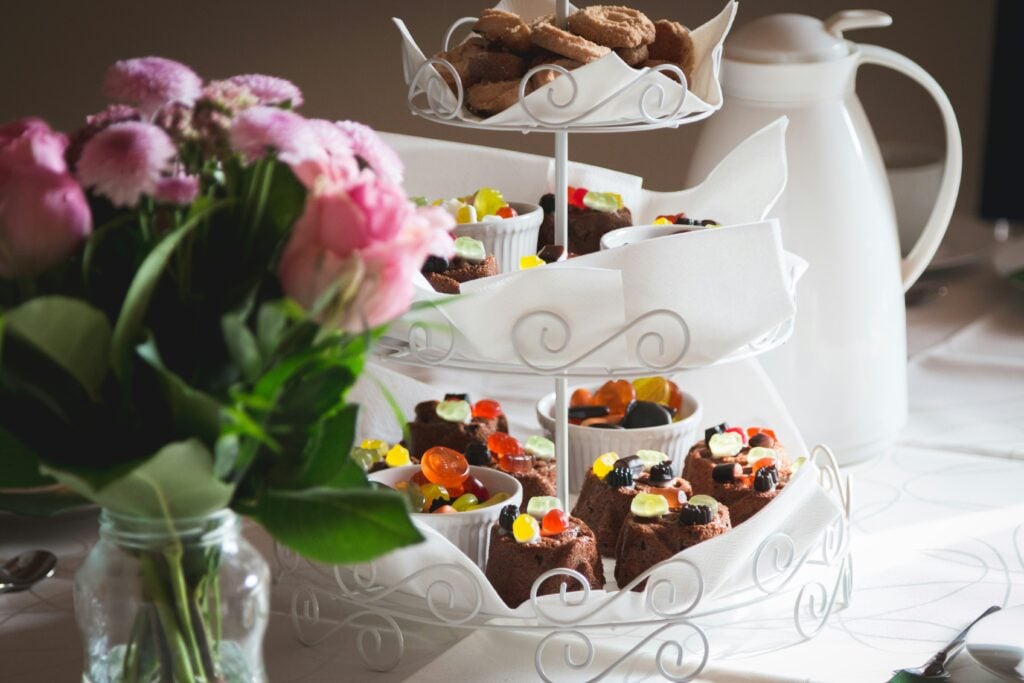 A three-tiered stand with sweets next to a vase of fresh flowers for a garden tea party.