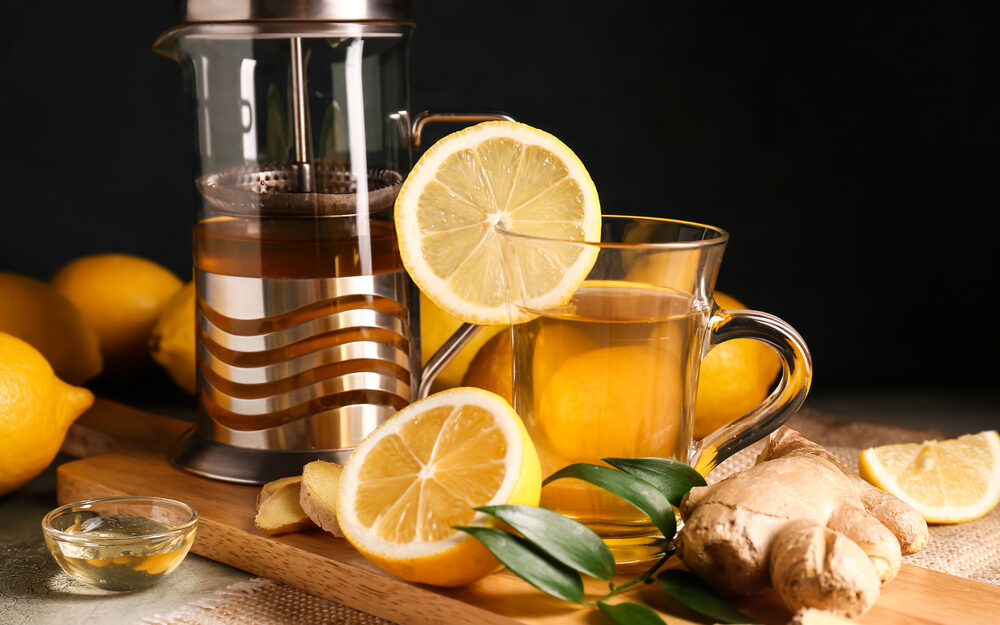 Teabloom tea press with borosilicate glass teacup, lemons, and fresh ginger root