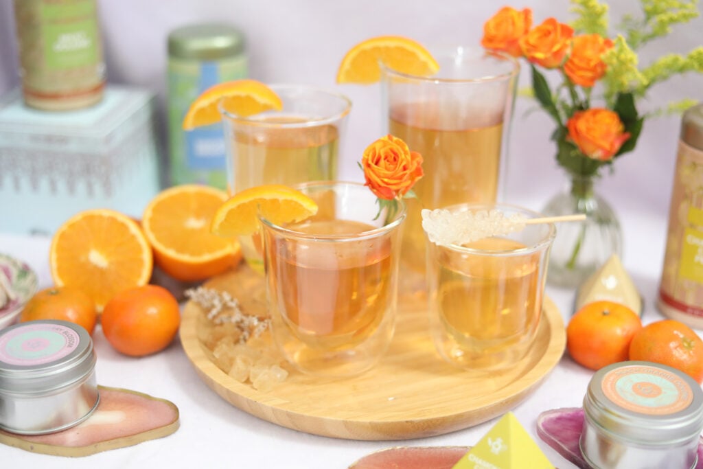 Teabloom cold brew tea cups with black tea, garnished with oranges, roses, and sugar sticks