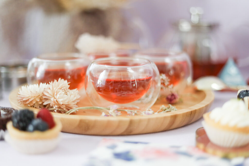 Teabloom round teacups with hot black tea, sweets, and flowers