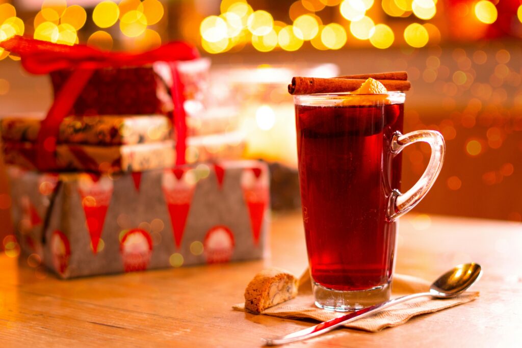 Glass teacup with cinnamon stick and orange next to a stack of presents