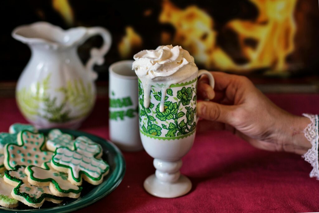 St. Patrick’s Day tea mug with whipped cream and a plate of shamrock cookies