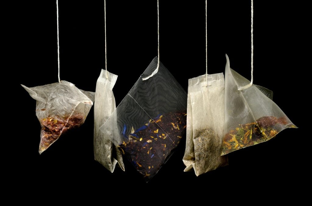 An assortment of tea bags and tea sachets against a black background.