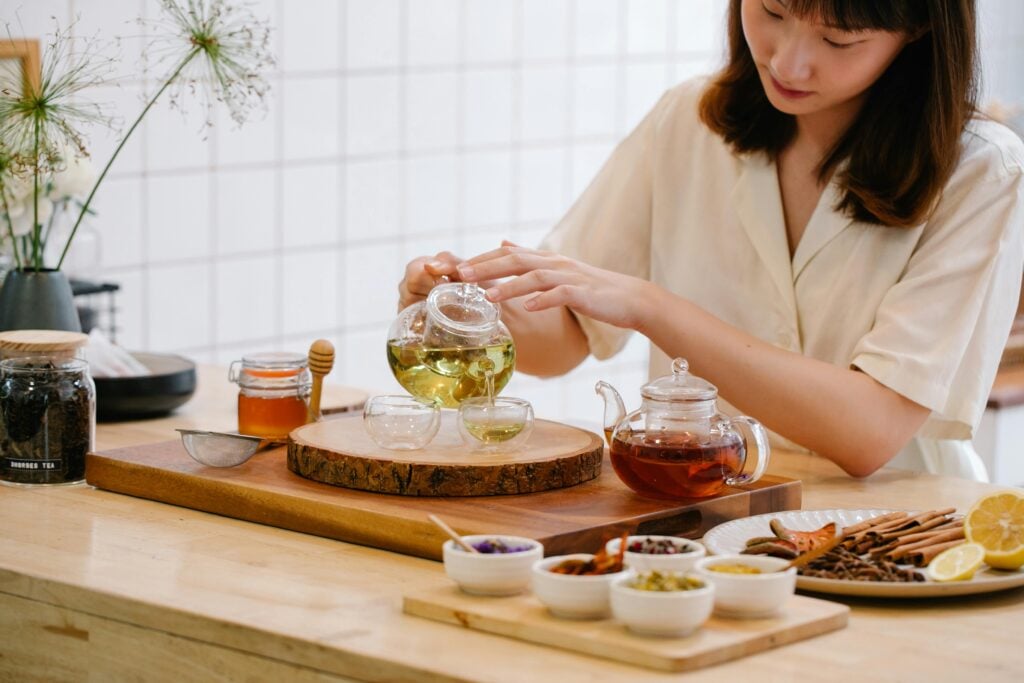 Woman pouring small size teapot with borosilicate glass cups and teaware