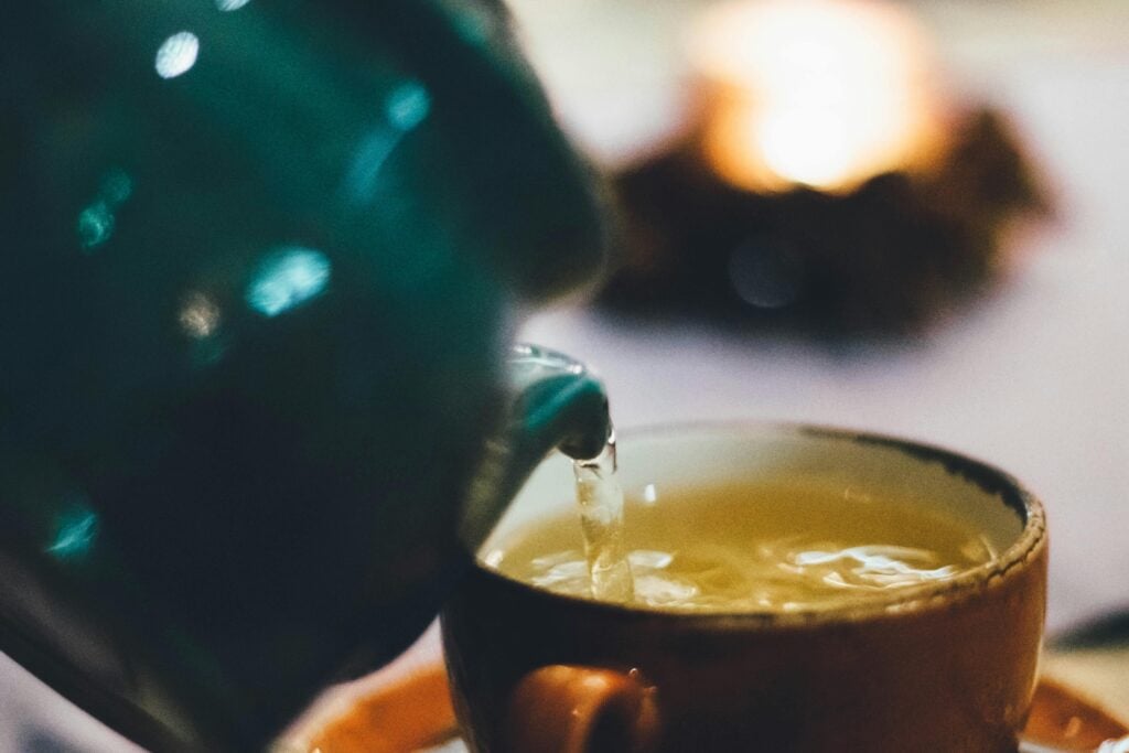 The best loose-leaf green tea being poured from a teapot into a teacup