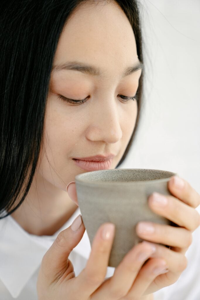Woman drinking the best loose-leaf green tea in a clay cup