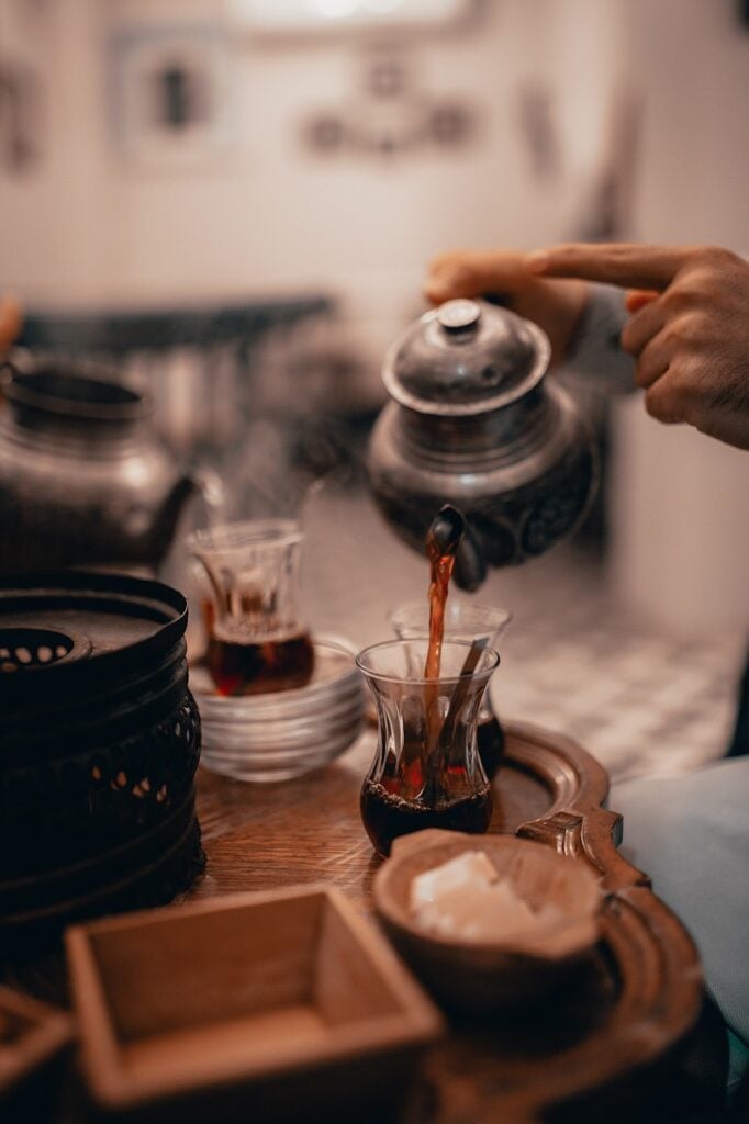 Maghrebi-style unique tea setup with tulip-shaped glasses, a metal teapot, sugar cubes, and saucers.