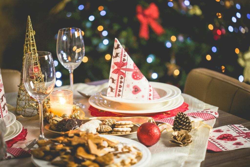 Christmas holiday tea party table setting with pinecones, cookies, ornaments, and holiday decor.