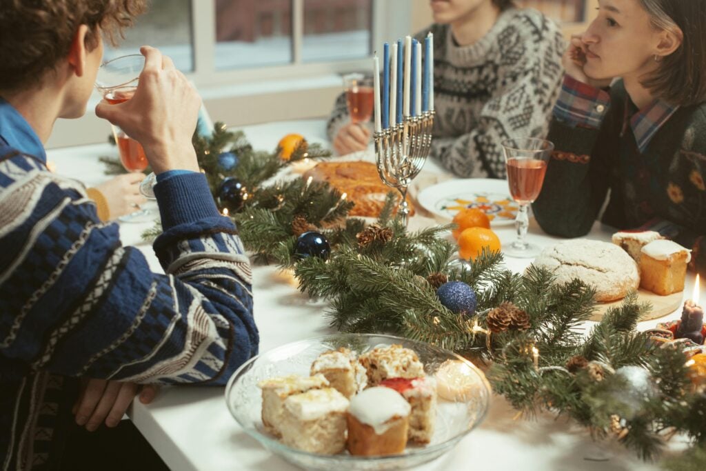 Hanukkah holiday tea party of a family at a table with a menorah, sweets, and tea.
