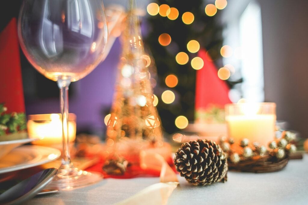 Holiday tea party tablescape with holiday decor against a holiday tree with lights.