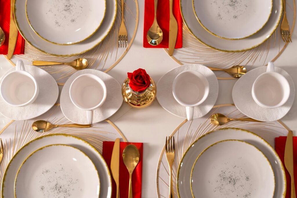White and gold holiday tea party tablescape with red napkins and white teacups.