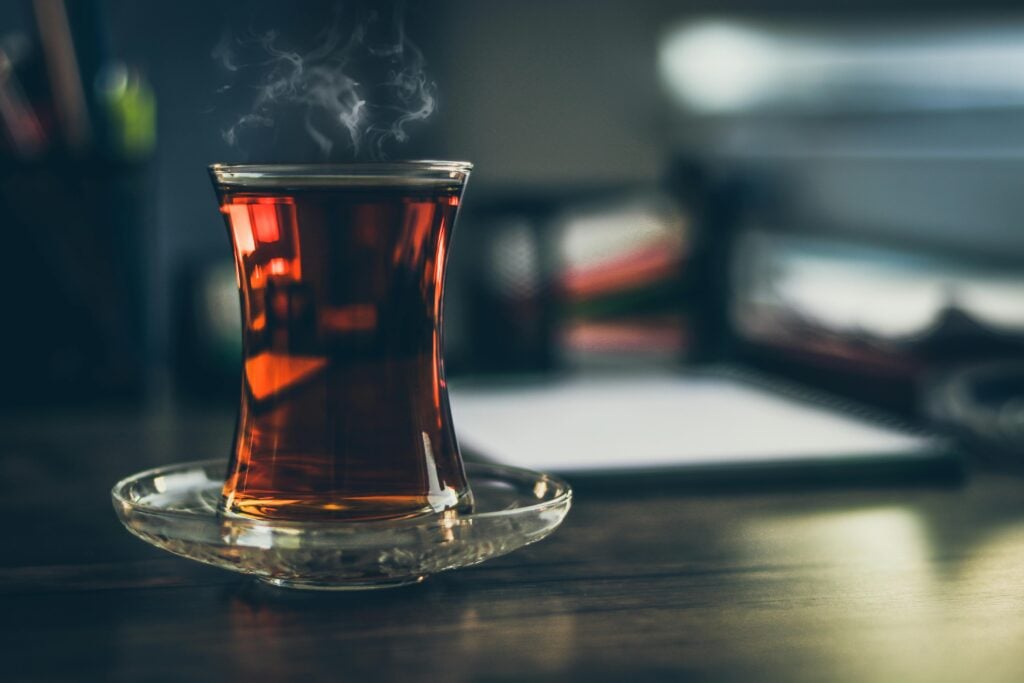 A glass tulip teacup and saucer with black tea is one of the best teas for energy.
