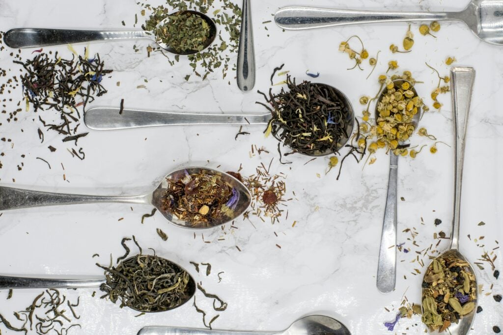 A marble table with silver spoons filled with dry herbs and tea for an upset stomach.